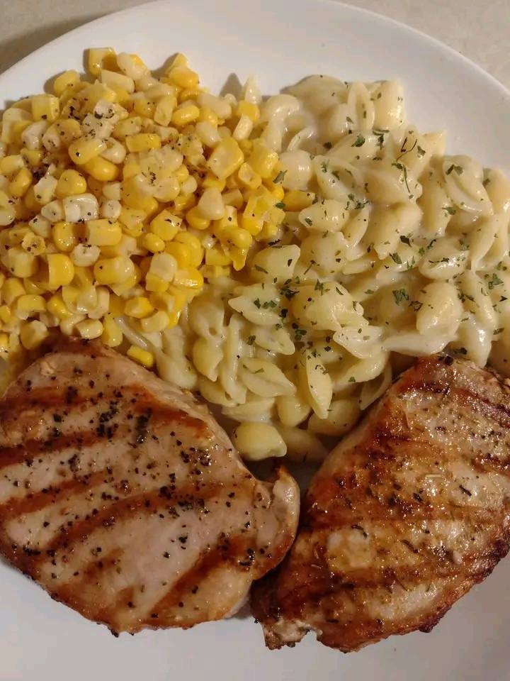 Grilled pork chops served with creamy garlic shells and buttered corn