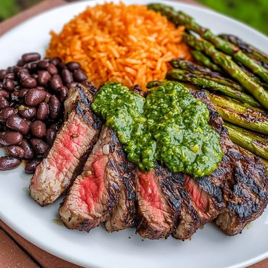 Grilled steak with chimichurri, orange rice, black beans, and grilled asparagus