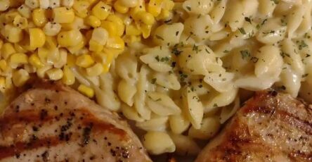 Grilled pork chops served with creamy garlic shells and buttered corn